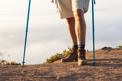 Close-up of male hiker legs. Traveler standing at edge of cliff. Sport, adventure, travelling concept