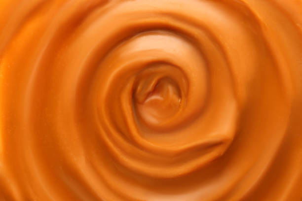 istock Liquid melted caramel syrup. Background of caramel syrup, paste. Curl, wave of caramel. Texture, Close up, top view. 1445010469