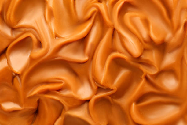 istock Liquid melted caramel syrup. Background of caramel syrup, paste. Curl, wave of caramel. Texture, Close up, top view. 1445010986