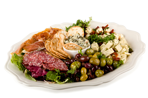 Italian antipasto on a plate with Bread Crackers, Cheese Dip, Prosciutto, Mozzarella Balls, Salami, Olives, and Cheese