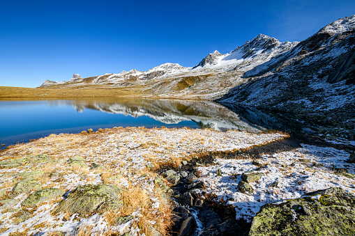 Altai mountains covered with snow and frozen lake with big stones