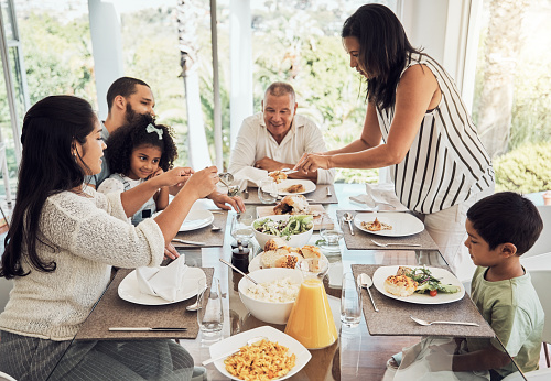 Lunch, eating food and big family in their Mexico home dining room table for summer reunion or quality time together. Puerto Rico mother, grandparents and children with chicken, salad and bread meal