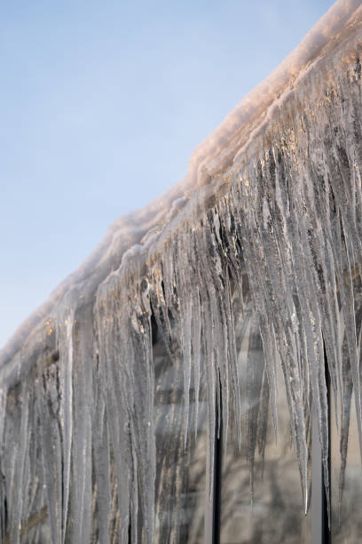 sople zwisają z dachu i ściany zimą. zamarznięta woda z topniejącego lodu i śniegu podczas wiosennej odwilży - melting ice icicle leaking zdjęcia i obrazy z banku zdjęć