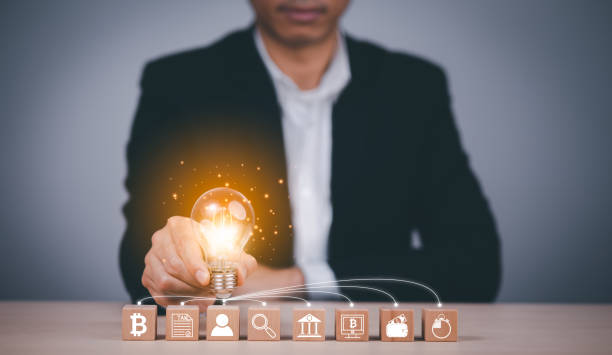istock Man hand holding light bulb with Business icon on wood cube and working on desk, Creativity, and innovation are keys to success. Concept of new idea and innovation with Brain and light bulbs. 1445018316