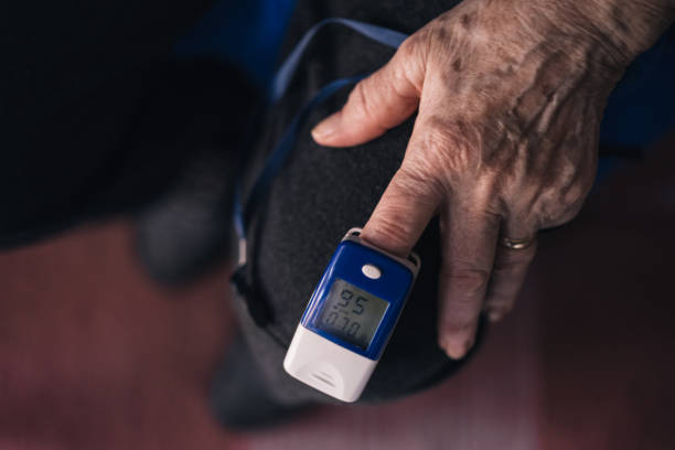 elderly woman measures her blood oxygen saturation using a pulse oximeter. home health concept - taking pulse oximeter medical oxygen equipment human lung imagens e fotografias de stock