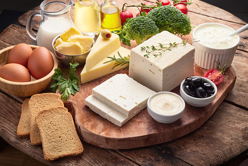 Fresh dairy products isolated on wooden background. Food collage of milk, cheese, butter, egg, vegetables, herbs, bread.