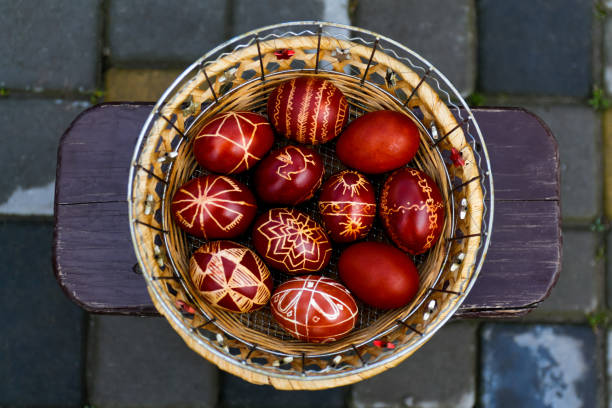 Defocus Closeup of basket of colored red eggs, Easter holiday concept. Modern painted easter eggs. Nature background, garden. Collection of pysanka or krashanka, Ukraine. Out of focus