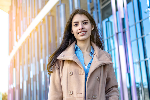 Smiling young businesswoman in front of office building with radiance