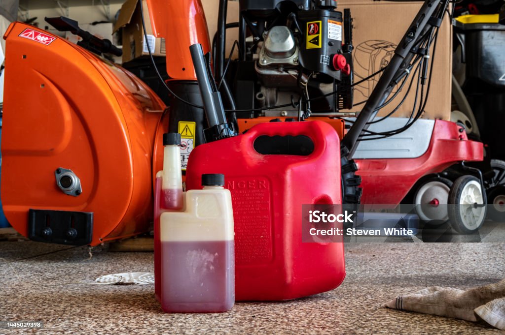 fuel stabilizer container for long term storage of gas in front of a portable canister and snow blower fuel stabilizer additive for gas in small engine equipment and storage Lawn Mower Stock Photo
