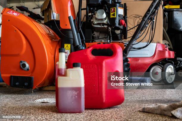 Fuel Stabilizer Container For Long Term Storage Of Gas In Front Of A Portable Canister And Snow Blower Stock Photo - Download Image Now