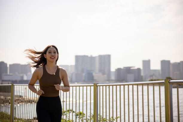 istock Female athlete running in waterfront public park 1445029618