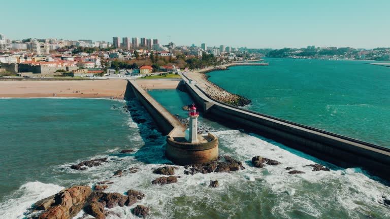 Drone view of Lighthouse Felgueirasin Porto with waves and cityscape, sunny day