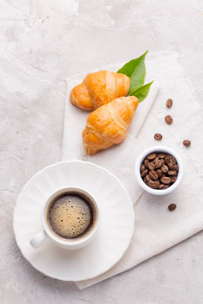 istock Coffee glass, roasted coffee beans and bread on the white table 1445032267