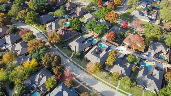 Upscale single family home with swimming pool and colorful fall foliage near Dallas, Texas, America. Aerial view an established suburban residential neighborhood bright autumn leaves, large street