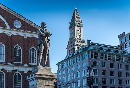 Boston, MA, USA - November 23, 2022: Tourists and locals strolling on the Dock square near the Samuel Adams statue at Faneuil Hall in Boston, MA. Samuel Adams was an American statesman, political philosopher, and one of the founding fathers of the United States.