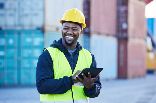 Logistics, tablet and black man shipping cargo on the internet while working at an outdoor warehouse. African industrial engineer thinking of strategy for distribution of stock on the web at a port