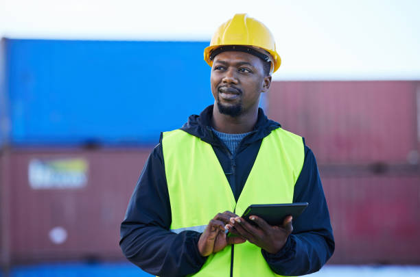 istock Tablet, black man and cargo planning logistics for shipping company, shipyard and container storage while confident. Business man, hard hat and strategy for freight import or export for supply chain. 1445043198