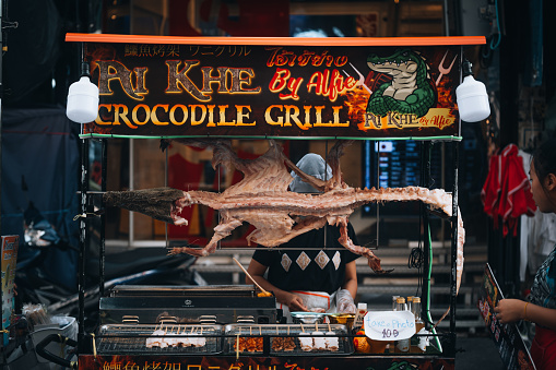 August 28, 2022 Bangkok, Thailand. Grilled crocodile put on display for sale at street food market in Patong.