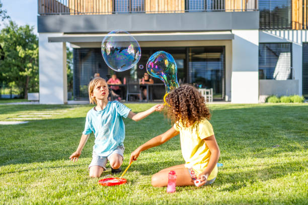 istock Multiracial brother and sister blowing huge soap bubbles in backyard 1445044671