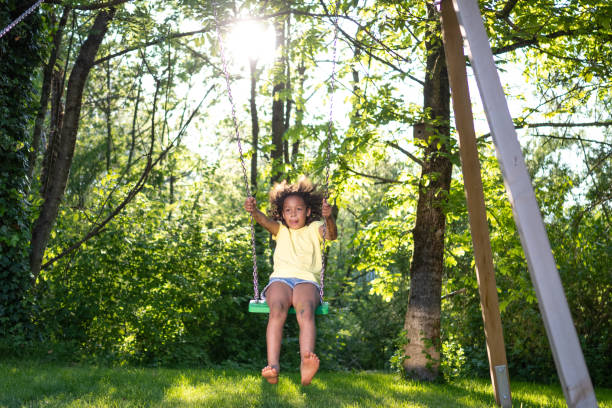 istock African american girl swinging in sunny backyard, front view 1445044672
