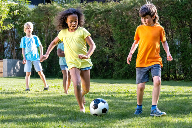 istock Diverse children playing soccer outdoors on summer 1445044689