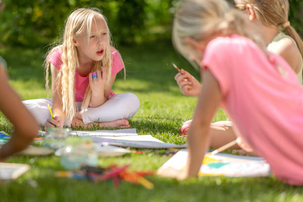 istock Girls group drawing outdoors, painting, sitting on backyard grass 1445044696