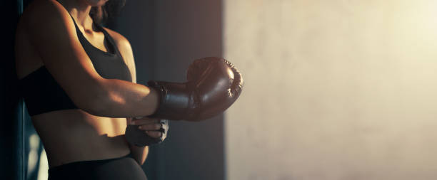 mujer joven de primer plano con guante de boxeo en el gimnasio. - boxing womens fotografías e imágenes de stock