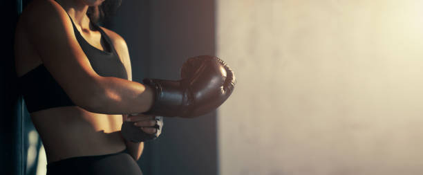 jeune femme en gros plan portant un gant de boxe dans le gymnase. - boxing womens photos et images de collection