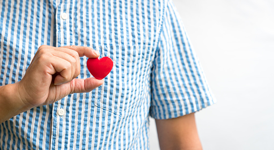 Man holding a red heart, close up view.