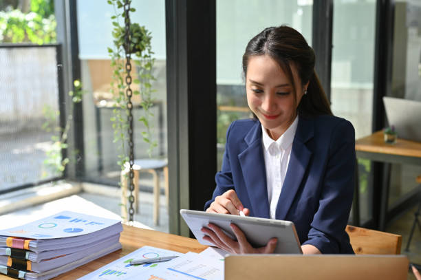 istock Attractive Asian businesswoman using a tablet, finding inspiration on internet, working at her desk. 1445068217
