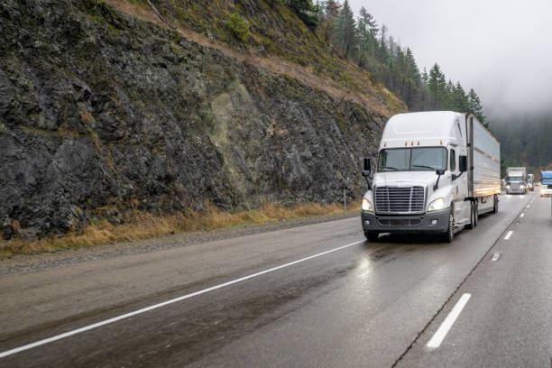 istock Big rig powerful white semi truck transporting cargo in refrigerator semi trailer running on the wet slippery road with fog 1445074021