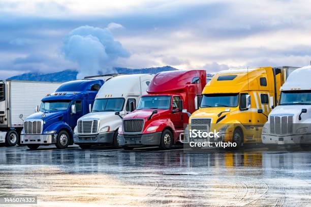 Bright Colorful Big Rigs Semi Trucks With Semi Trailers Standing In The Row On Truck Stop Parking Lot At Early Morning Stock Photo - Download Image Now