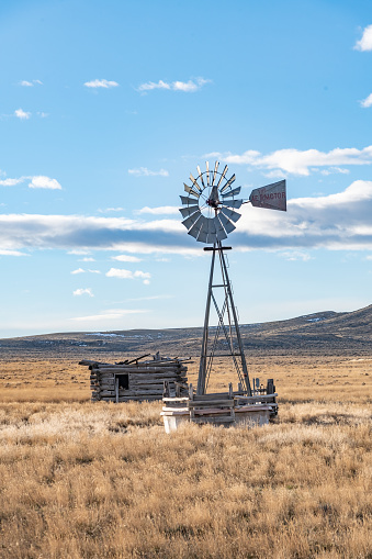 Old style bladed windmill and log cabin on Montana prairie in northwestern USA.