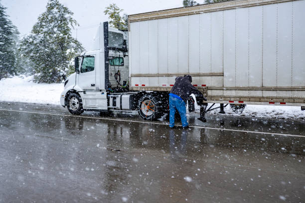 un chauffeur de camion met des chaînes sur les roues du gros semi-remorque avec semi-remorque pour conduire en toute sécurité sur une autoroute d’hiver pendant une tempête de neige dans la région du lac shasta en californie - semi truck truck red truck driver photos et images de collection