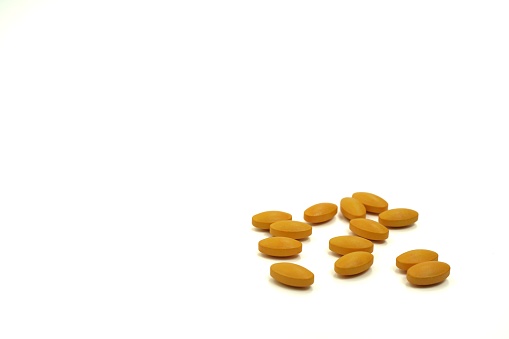 The picture shows multivitamin orange tablets for lowering blood sugar on a white background, copy space.