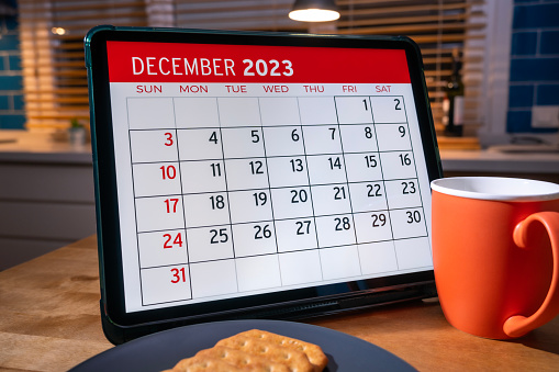 Tableta con calendario de diciembre 2023 en pantalla sobre la mesa de la cocina. photo