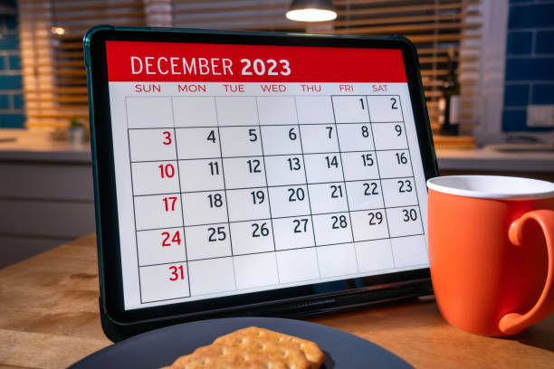 tablet computer with 2023 december calendar on screen above kitchen table. - december stockfoto's en -beelden