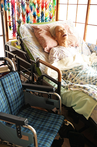 Elderly woman with dementia lying in a nursing bed