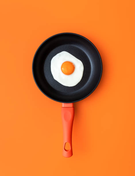 Fried egg in a cooking pan, top view on an orange background stock photo