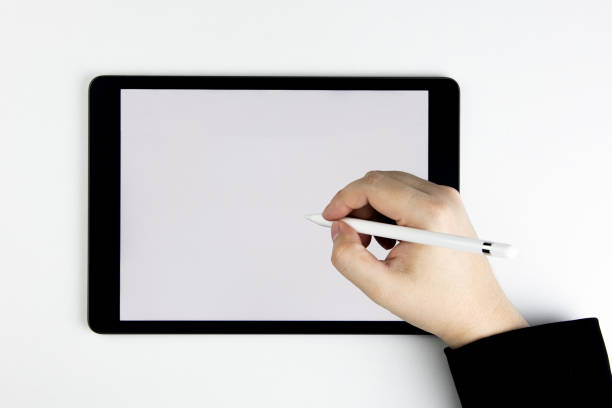 istock Top view of hand holding pen writing tablet computer with blank white screen. 1445081478
