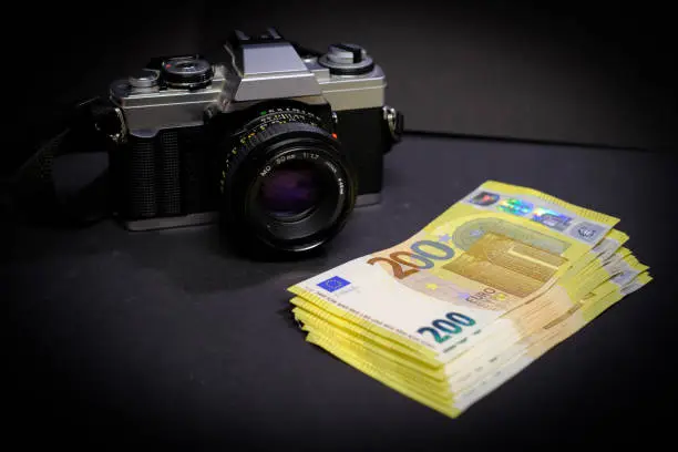 next to an old reflex camera lies a stack of 200-Euro banknotes