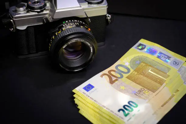 next to an old reflex camera lies a stack of 200-Euro banknotes