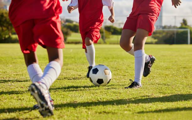 kids team, soccer or legs with soccer ball in workout, fitness game or exercise on nature park grass, high school stadium or field. football or sports training with energy in health or girls wellness - elementary age child group of people togetherness imagens e fotografias de stock