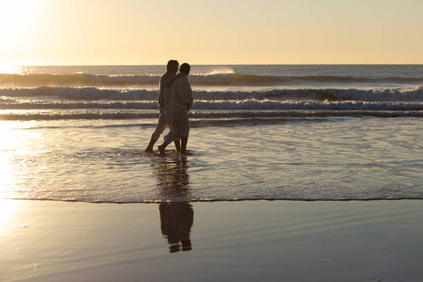 istock Senior couple walking along seashore at sunset 1445103057