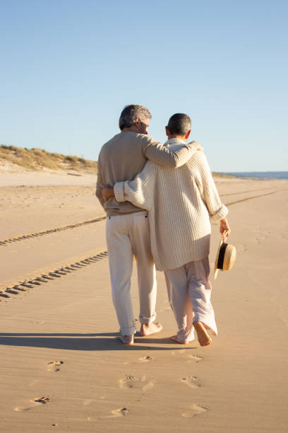 istock Senior couple walking barefoot on the beach 1445103211