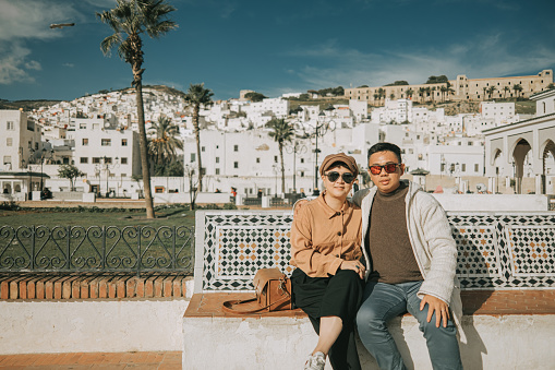 Asian Chinese Tourist couple looking at camera in front of old town Tetouan, Morocco during sunset