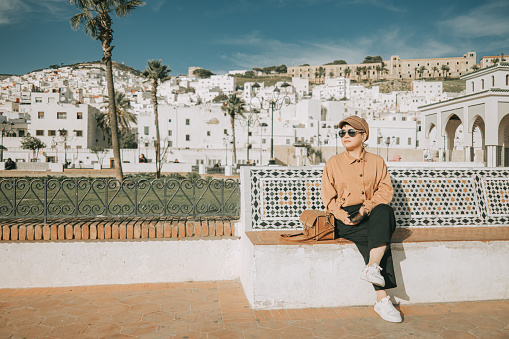 Asian Chinese Female Solo Tourist sitting in front of old town Tetouan, Morocco during sunset