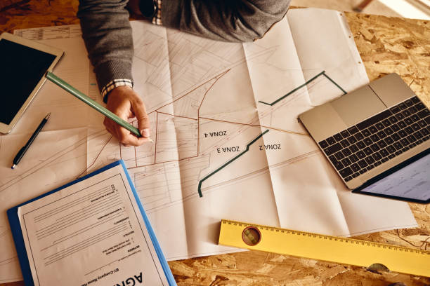 istock Above view of an architect examining blueprints in the office. 1445109682