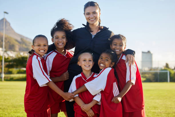 Football, happy and girl team with coach on a sport soccer field after training or a game. Teamwork, collaboration and support with a happy group of female athletes ready to support, win and success fútbol, equipo feliz y femenino con entrenador en un campo de fútbol deportivo después de un entrenamiento o un partido. el trabajo en equipo y la colaboración con un grupo feliz de atletas femeninas juegan por diversión, para ganar y tener éxito