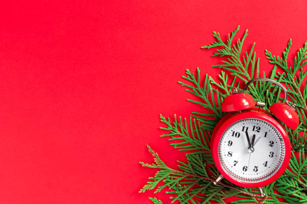 istock Alarm clock  with tree branches on red paper background. 5 minutes before the New Year. Creative greeting card. 1445111917